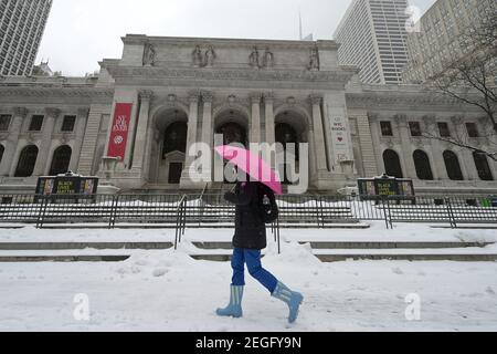 New York, USA. Februar 2021, 18th. Eine Frau, die einen rosa Regenschirm hält, geht an der New York City Public Library entlang der Fifth Ave. Vorbei während eines Wintersturms, der in den nächsten zwei Tagen mehr als einen Fuß Schnee bringen wird, New York, NY, 18. Februar 2021. Der National Weather Service hat eine Wintersturmwache für das Tri-State-Gebiet herausgegeben, da ein Großteil der Nation in den letzten Tagen unter Winterexplosion leidet. (Foto von Anthony Behar/Sipa USA) Quelle: SIPA USA/Alamy Live News Stockfoto