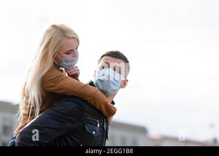 Junges Paar umarmt trägt eine Gesichtsschutzmaske in der Innenstadt, da neue Coronavirus entstanden sind. Stockfoto