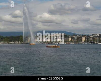 Gelbe Fährschiffe fahren am Brunnen am Genfer See in der Stadt genf vorbei Stockfoto
