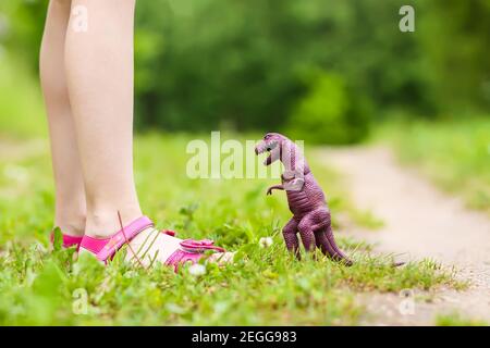 Kleines Mädchen spielt mit dem Kunststoff-Dinosaurier-Spielzeug im Frühjahr parken Stockfoto