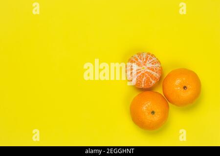 Mandarinen auf gelbem Papierhintergrund. Heller Rahmen mit Mandarinen, Kopierraum für Text. Vorlage, Muster. Zitrusfrüchte Draufsicht. Lustige Sommerstimmung Stockfoto