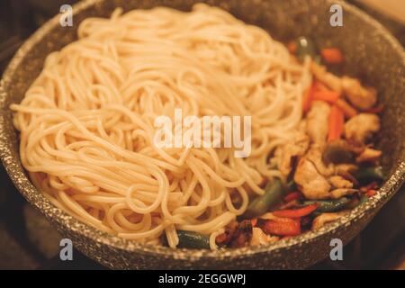 Gebratene Nudeln mit Gemüse und putenfleisch in schwarz Bügeln Sie die Wok-Pfanne an Stockfoto