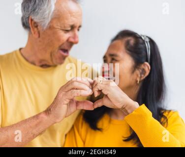 Glückliches altes Paar, das mit den Händen ein Herz macht Stockfoto