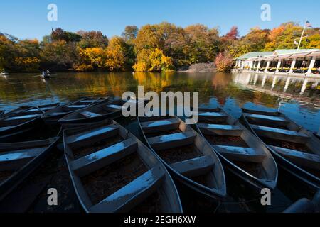 Viele Ruderboote sind auf dem See rund um das Bootshaus verankert, die im Central Park in New York City N von Laubbäumen umgeben sind Stockfoto