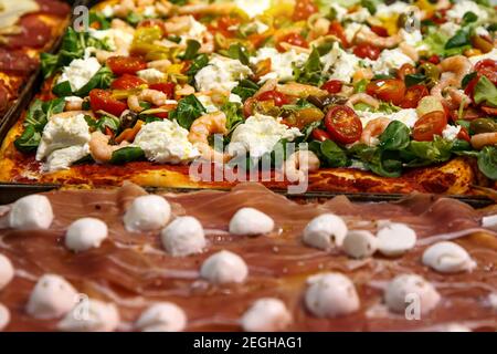 Heiß und lecker. Pizzascheiben mit Schinken-Jamon und Käse. Traditionelle italienische Focaccia mit Tomaten, schwarzen Oliven und Käse Stockfoto