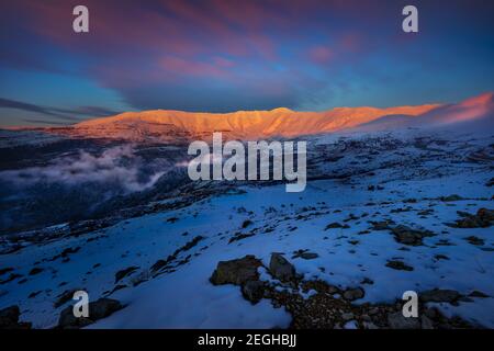 Abends Blick auf eine wunderschöne Berge bedeckt mit Schnee in hellen Sonnenuntergang Licht. Winterlage. Tannourine. Libanon. Stockfoto