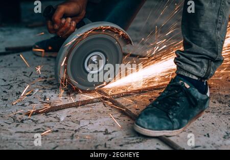 Stahlschneider Säge bei der Arbeit. Nahaufnahme Foto eines heißen hellen Sparks Fliege aus unter dem Schweißenden, harte Arbeit, Blue Collar Worker. Stockfoto