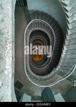 Alte Wendeltreppe aus Beton mit Metallgeländern und Lampen unten Stockfoto