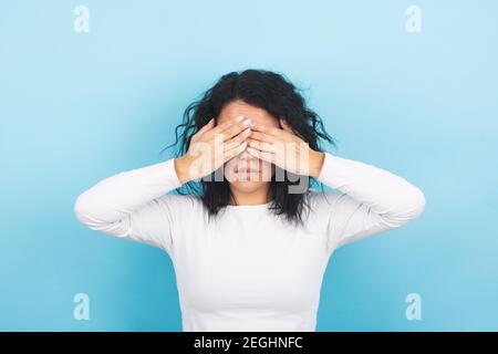 Junge Brünette Frau bedeckt ihre Augen mit ihren Händen Stockfoto