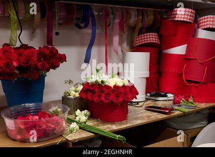 Blumenkasten mit roten Rosen und weißen Blumen auf dem Tisch, Blumenkasten Montageprozess Stockfoto