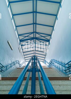 Betontreppe zum Bahnsteig mit Metalldach und blau Geländer Stockfoto