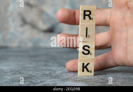 Risiko schreiben mit schwarzen Buchstaben auf Holzdices und ein Mann hält es mit der Hand Stockfoto