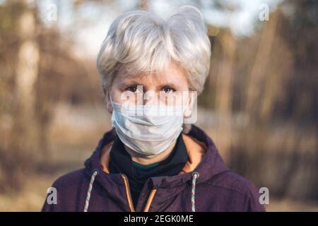 Nahaufnahme Porträt einer schweren Frau mittleren Alters, die in der Straße in einer medizinischen Maske steht. Das Konzept der Prävention und des Schutzes während einer Pandemie Stockfoto