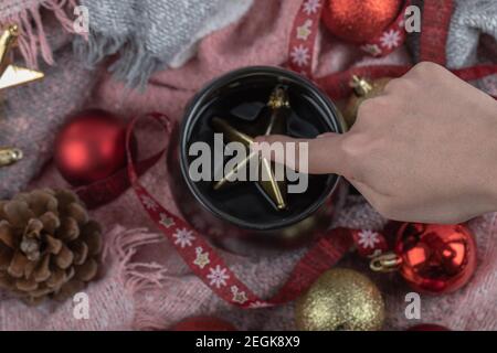 Einen goldenen Weihnachtsstern in einen Trinkbecher geben Stockfoto