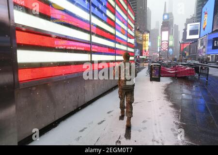 18. Februar 2021 : EIN leichter Schneesturm traf New York City. Ein US-Soldat, der durch den Schnee am beleuchteten vorbeiläuft Stockfoto