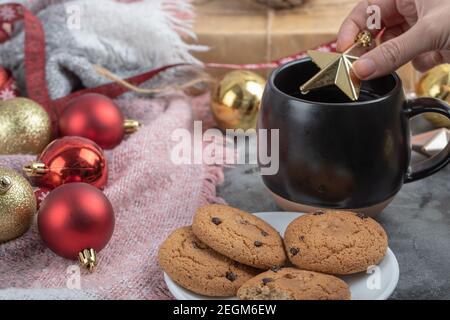 Einen goldenen Weihnachtsstern in einen Trinkbecher geben Stockfoto