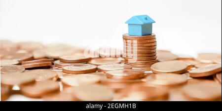 Immobilien-Banner Home Geld Münzen Turm Gewinn Immobilien-Investitionen oder Haushaltseinkommen. Miniatur-Home-Modell auf Stapel Münzen Gebäude Geld Stockfoto