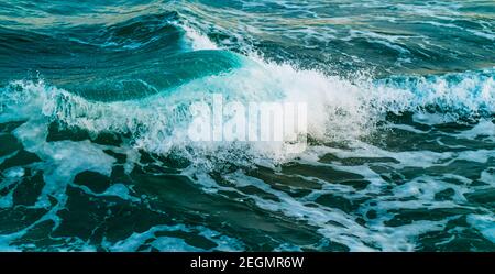 Erstaunliche türkisfarbene Wellen und weißer Schaum. Wellen krachen an der Küste. Blaues Meerwasser. Eine lebendige Meereslandschaft für einen Urlaubsort. Stockfoto