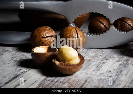 Macadamianüsse und Nussknacker auf Holztisch Stockfoto