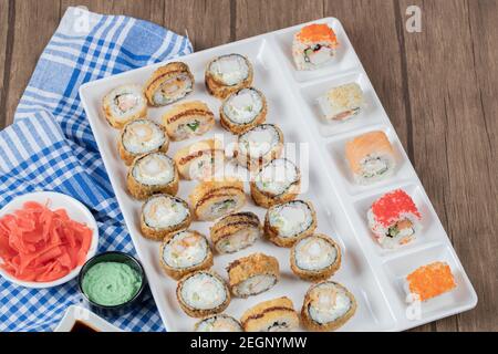 Gebratene heiße Sushi-Brötchen mit Sojasauce, Wasabi und Ingwer auf einem blau karierten Handtuch Stockfoto
