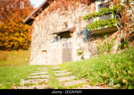 Steinweg vor verschwommenem traditionellen italienischen Haus in der Landschaft. Stockfoto