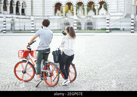 Junge Touristen Paar in Masken machen Ausflug auf dem Fahrrad. Mann und Frau Fahrradfahrer fotografieren Wahrzeichen der Stadt. Mailand, Italien - 26. Mai 2020 Stockfoto