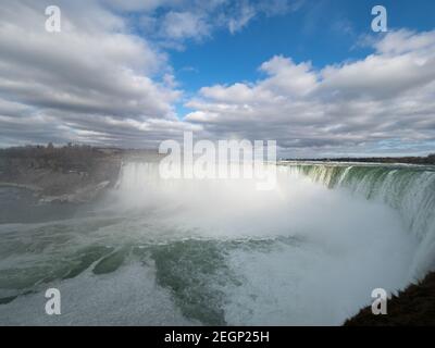 Regenbogen gebildet im Wassernebel an den Niagarafällen, Horseshoe kanadische Seite, grünes Wasser und blauer Himmel Stockfoto