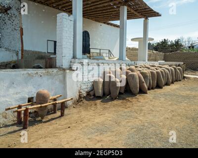 Viele Keramikvasen gärten Pisco und Wein, die auf dem Boden in einer Wein- und Pisco-Fabrik in peru vor einer weißen Wand saßen Stockfoto