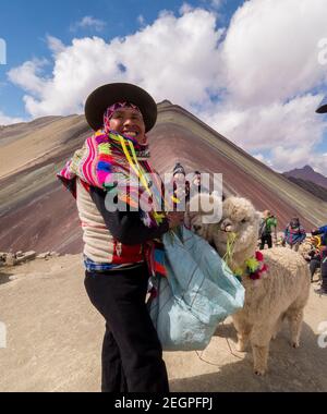 Peru, Vinicunca - 27. September 2019 - Inder begleitet von Lamas lächelt am Regenbogenberg Stockfoto