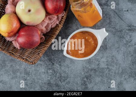 Pfirsich und Äpfel in einem Holzkorb auf einem Stück Von rosa Handtuch Stockfoto