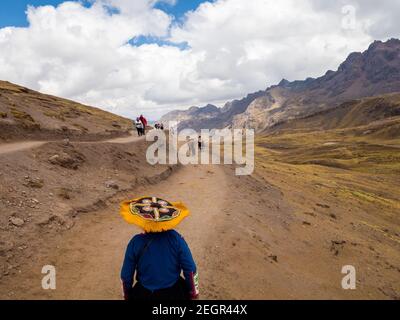 Peru, Vinicunca - 1. Oktober 2019 - Indische Frau von hinten betrachtet genießt Blick auf die Anden, Touristen und Pferde zu Fuß auf Feldweg Stockfoto