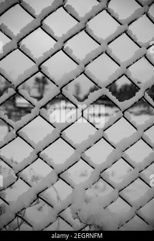 Vertikale Aufnahme von Schnee auf einem Kettengliederzaun - Winterhintergrund Stockfoto