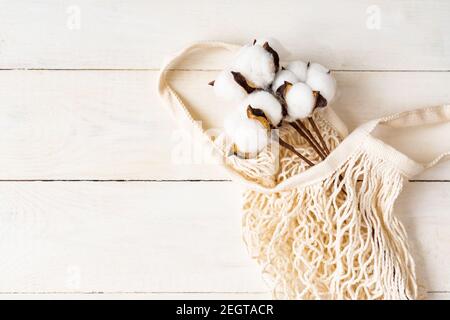 Weiße Öko-Tasche Mesh-Textur mit Baumwollzweig auf einem natürlichen Holz weißen Hintergrund. Stockfoto
