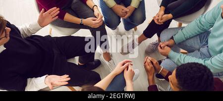 Draufsicht auf verschiedene Menschen, die in einem engen Kreis sitzen und mit einem Therapeuten sprechen. Stockfoto