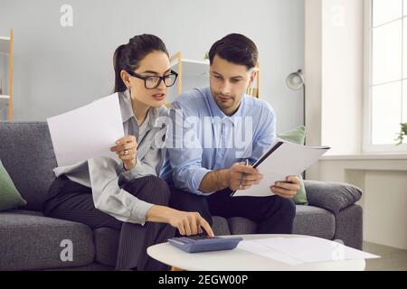 Junges Paar sitzt auf dem Sofa, Ausfüllen der Steuererklärung oder Blick durch Stromrechnungen Stockfoto