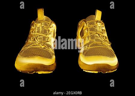 Goldene Turnschuhe schwarzer Hintergrund isoliert Nahaufnahme, Gold Metall Sportschuhe, Luxus Laufen Gummischuhe, Mode gelb metallic Fitness Stiefel, Schuhe Stockfoto