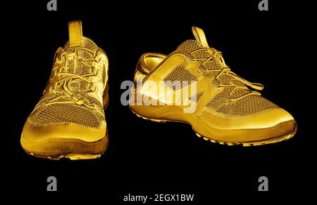 Goldene Turnschuhe schwarzer Hintergrund isoliert Nahaufnahme, Gold Metall Sportschuhe, Luxus Laufen Gummischuhe, Mode gelb metallic Fitness Stiefel, Schuhe Stockfoto