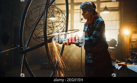 Talented Emerging Female Artist verwendet einen Disc Grinder, um eine abstrakte, brutale Metallskulptur zu machen, die den gegenwärtigen Moment widerspiegelt. Wunderschöner Tomboy Stockfoto