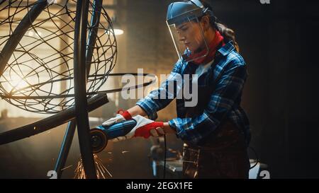 Talented Emerging Female Artist verwendet einen Disc Grinder, um eine abstrakte, brutale Metallskulptur zu machen, die den gegenwärtigen Moment widerspiegelt. Wunderschöner Tomboy Stockfoto