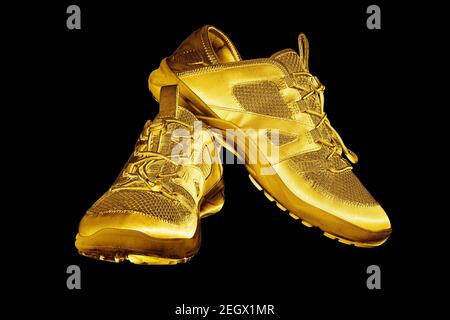 Goldene Turnschuhe schwarzer Hintergrund isoliert Nahaufnahme, Gold Metall Sportschuhe, Luxus Laufen Gummischuhe, Mode gelb metallic Fitness Stiefel, Schuhe Stockfoto