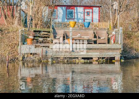 Holzveranda am Wasser mit Geländern aus Seilen und Bojen in einem traditionellen skandinavischen Sommerhaus. Es vermittelt Minimalismus und Intimität Stockfoto