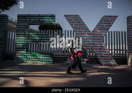 18. Februar 2021, Mexiko, Tijuana: Eine mexikanische Migrantin trägt ihren Sohn, als sie auf eine Gruppe von humanitären Asylbewerbern zugeht. Zentralamerikanische und mexikanische Migranten, die Flüchtlinge im Flüchtlingsheim Agape sind, demonstrierten vor dem Haupteingang des Grenzübergangs El Chaparral an der Grenze zwischen Tijuana, Mexiko, Und San Diego, Kalifornien, mit dem Ziel, die US-Behörden zu bitten, die Grenze zu öffnen und den Prozess für die Gewährung von politischem Asyl für Flüchtlinge neu zu starten. Nach dem Richtungswechsel in der Migrationspolitik erlaubt die US-Regierung erneut Asylbewerber quer durch das b Stockfoto