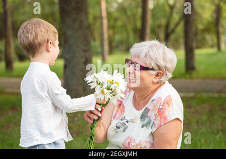 Schöner Junge, der Großmutter eine Blume gibt. Alles gute zum Muttertag. Stockfoto