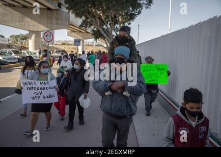 18. Februar 2021, Mexiko, Tijuana: Eine Gruppe von Migranten, bestehend aus Männern, Frauen und Kindern, geht an den Grenzübergang, um Informationen über ihren Einwanderungsprozess zu erhalten. Zentralamerikanische und mexikanische Migranten, die Flüchtlinge im Flüchtlingsheim Agape sind, demonstrierten vor dem Haupteingang des Grenzübergangs El Chaparral an der Grenze zwischen Tijuana, Mexiko, Und San Diego, Kalifornien, mit dem Ziel, die US-Behörden zu bitten, die Grenze zu öffnen und den Prozess für die Gewährung von politischem Asyl für Flüchtlinge neu zu starten. Nach dem Richtungswechsel in der Migrationspolitik, die US-Regierung i Stockfoto