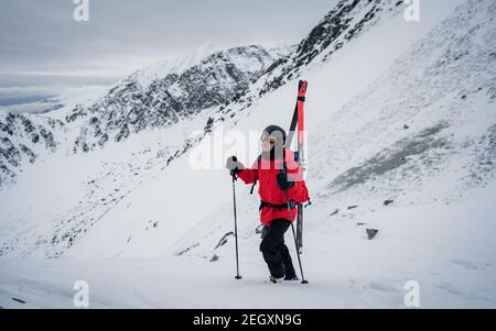 Skifahrer steht auf dem Berg und blickt auf die wunderschöne Landschaft. Winter Extremsportkonzept. Rückansicht eines stark motivierten Mannes Stockfoto