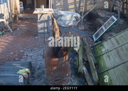 Alte hölzerne Zaunpfosten Brennen in einer Verzinkungsanlage aus Metall auf einer Baustelle in Rural Devon, England, Großbritannien Stockfoto