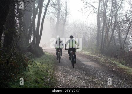 Lonate Pozzolo, Varese - Italien - Dezember 13.2020 Radler fahren im Winter Wege im Wald. Stockfoto