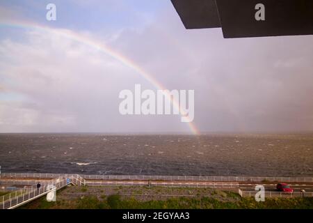 Regenbogen bei Afsluitdijk, einem Damm, der die Nordsee vom Ijsselmeer trennt. Blick von der Brücke auf Breezanddijk, eine künstliche Insel von bui geschaffen Stockfoto