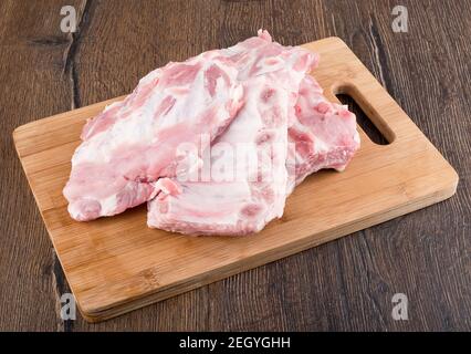 Gehackte Stücke von rohen Schweinefleisch Rippen auf einem Schneidebrett. Nahaufnahme. Stockfoto