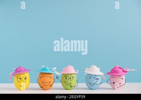 Glückliche Eier in Hüten lachen. Osterfeiertagskonzept mit niedlichen Eiern mit lustigen Gesichtern. Verschiedene Emotionen und Gefühle. Stockfoto